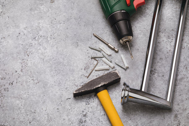 把锤子、钻头和毛巾架放在有复印空间的桌子上，俯视图。在浴室里安装加热毛巾架的概念图片下载