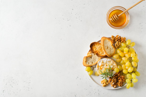 盘子里有烤卡门贝尔奶酪、面包片和绿葡萄图片下载