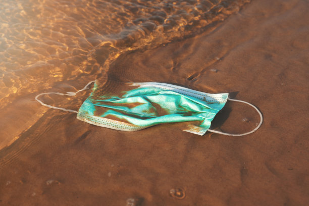 传染性废物-医用口罩在海水中的沙滩上。2019冠状病毒病以来的海洋污染图片下载