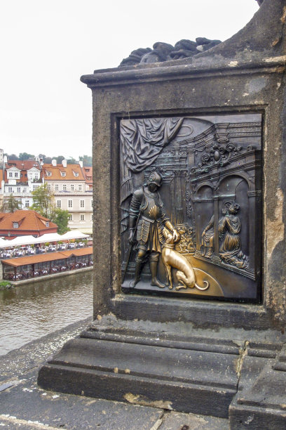 一只狗和一个守卫在克莱斯桥上的图片，背景是河流和城市的一部分。图片下载