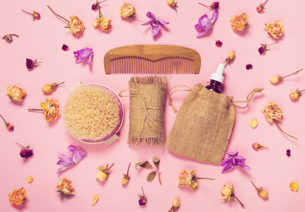 一套天然肥皂，香油，木制梳子和身体按摩刷与干玫瑰和兰花芽作为装饰图片下载