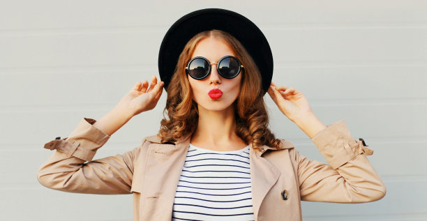 近距离的肖像迷人的女人吹红唇送甜蜜的空气吻在灰色的背景图片下载