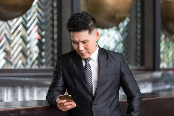 亚洲商人，黑色西装，短发，英俊潇洒，使用手机图片下载
