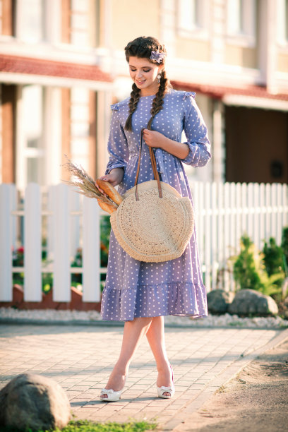 一个手里拿着法棍的漂亮女人在街上的肖像。穿着土里土气的女孩很有感情。图片下载