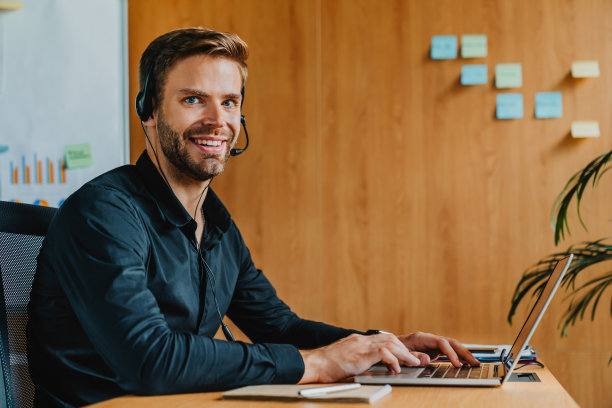 肖像商人在办公室用耳机和笔记本电脑打电话，帮助线。Teleconsulting图片下载