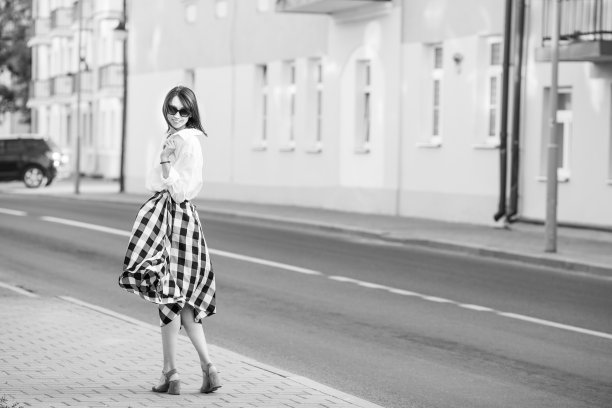 幸福理念——快乐的女人在城市街道上玩乐。戴着墨镜的时尚女子踩着高跟鞋走在街上。黑白图像。本空间图片下载