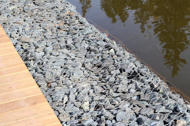 砂砾覆盖着金属丝的地面，背景照片纹理，俯视图。金属格栅下碎石制成的滑坡防护图片下载