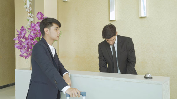 商务客人度假旅行时，在酒店大堂前台接待或礼宾处办理入住或预订手续。图片下载