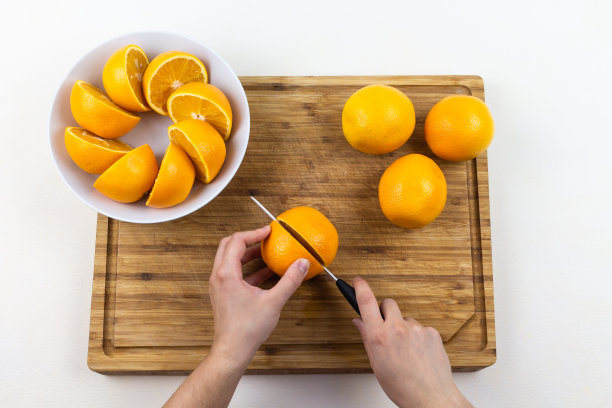 手在木砧板上切橘子，盘子上有切好的橘子图片下载