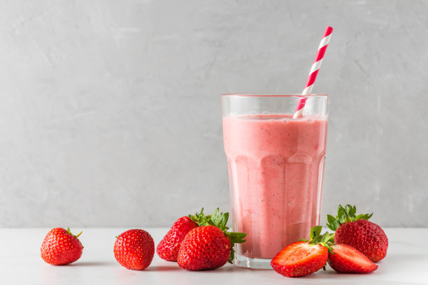 草莓冰沙或奶昔在玻璃杯中与一根吸管和新鲜的浆果在白色的背景。夏天喝图片下载