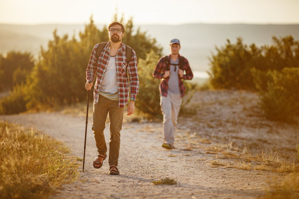 两个徒步旅行者在夏日夕阳西下的大自然中漫步图片下载