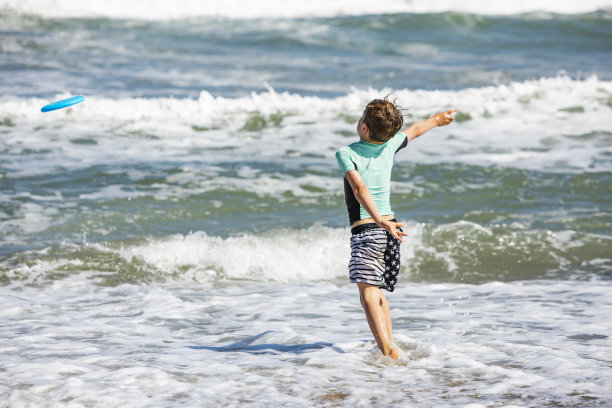 父亲和儿子在海滩玩飞盘图片下载
