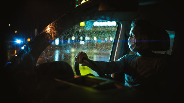 戴着医用口罩的人在雨夜路上开车图片下载