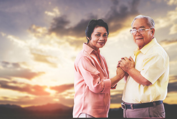 在金色天空的自然背景下，资深亚洲夫妇手牵手，表达爱和团聚的理念。图片下载