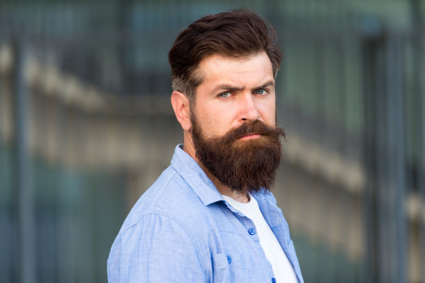 满脸胡须的男人。理发店,理发师。男性美。发型技巧。用胡须创造个人风格。时髦的胡子和小胡子城市背景的潮人图片下载