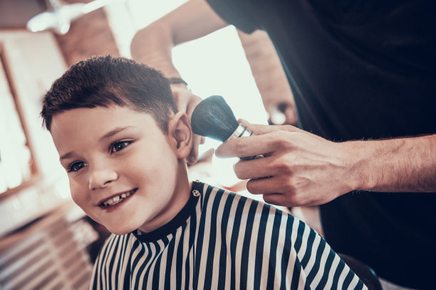 男孩理发后坐在理发店的椅子上。图片下载