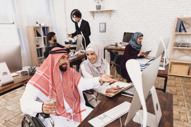 阿拉伯女孩和男人坐在工作桌旁讨论。图片下载