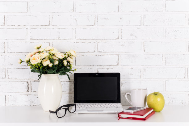 在白砖墙的桌子上放着现代的笔记本电脑图片下载
