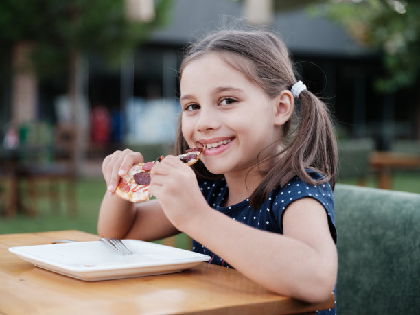 快乐的孩子女孩在晚上吃她的披萨在户外餐厅图片下载