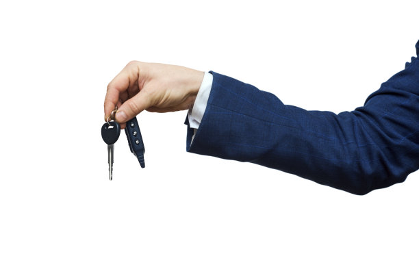 商人拿着车钥匙，孤立在白色背景上。商人提供汽车钥匙。司机的手显示他自己的汽车钥匙的特写图片下载
