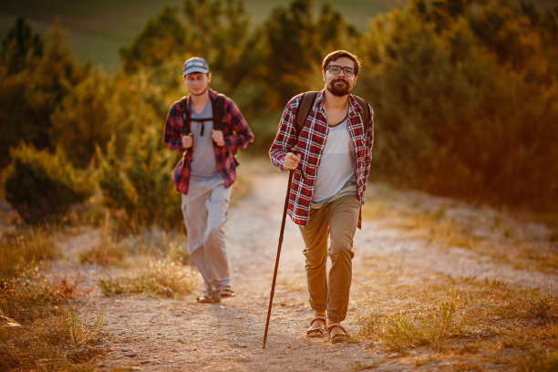 两个徒步旅行者在夏日夕阳西下的大自然中漫步图片下载