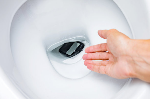 手机在厕所，概念。一个女人把手机掉进马桶里了。图片下载