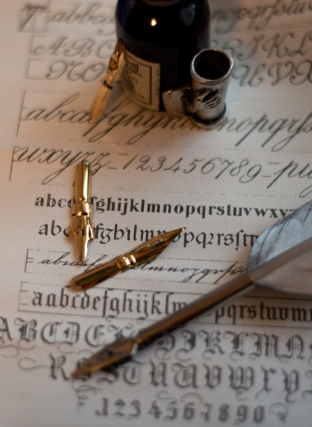 一张带有旧墨水瓶的钢笔照片，在纸莎草纸上有几个不同形状的笔尖和书法例子。图片下载