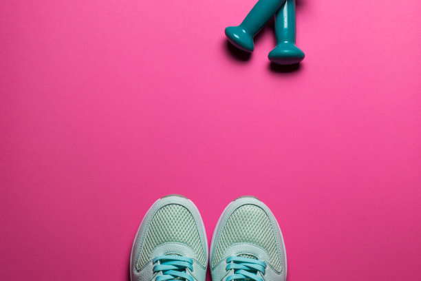 绿松石运动鞋和哑铃在粉红色的背景特写图片下载