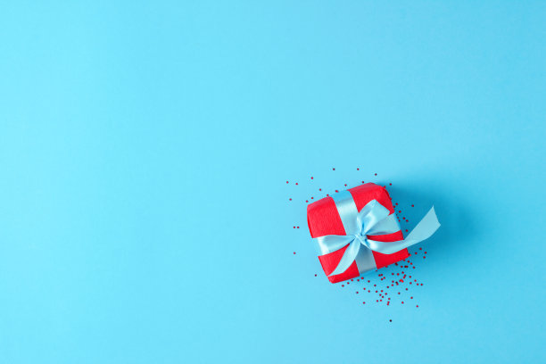 蓝色背景上有五彩纸屑的红色礼物。圣诞节或假日概念。平铺，拷贝空间图片下载