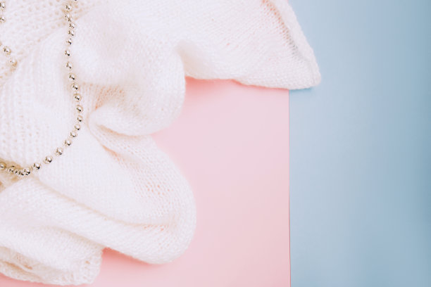 白色针织面料和银色的珠子在粉红色和蓝色的背景图片下载