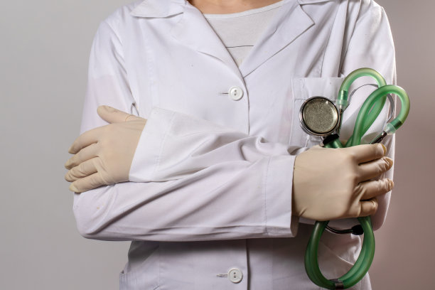 绿色的听诊器。一名身穿白色医疗制服、戴着手套的医生拿着听诊器。图片下载