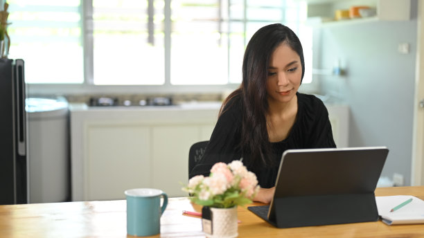 在公寓里用平板电脑工作的女性。图片下载