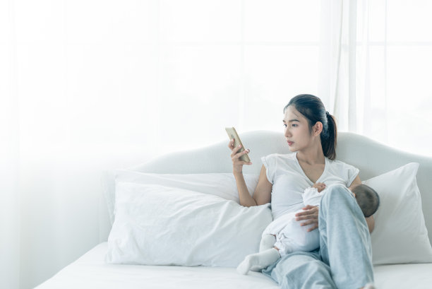 单身忙碌的妈妈一边喂宝宝一边忙着打电话。新生儿正在接受母亲的母乳喂养。图片下载