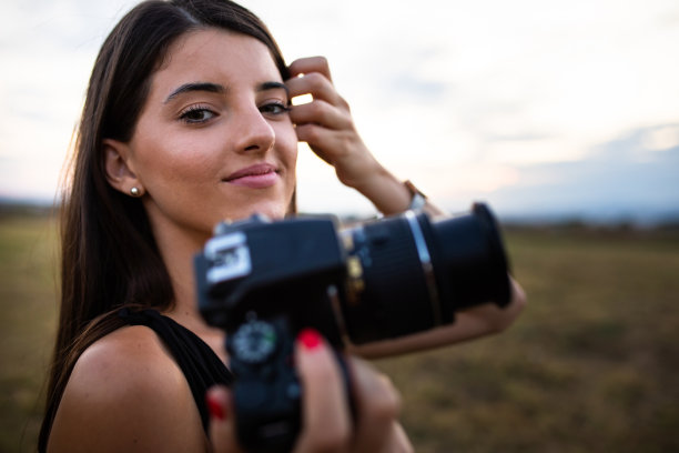 一个漂亮的年轻女人拿着相机微笑着图片下载