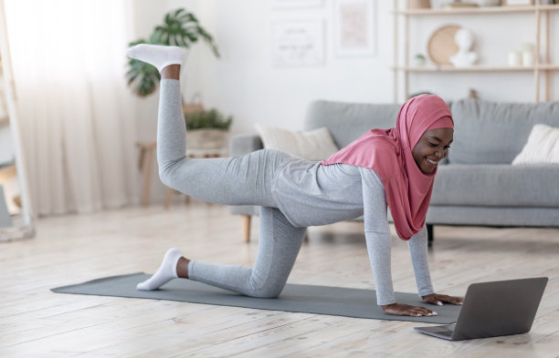 运动黑人伊斯兰妇女戴着头巾在家用笔记本电脑健身图片下载
