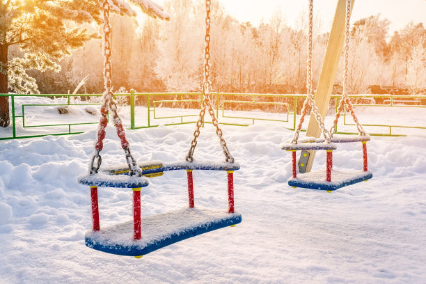 明亮的操场上的雪在一个阳光明媚的冬日。孩子们的秋千在冰雪覆盖的冬季操场上荡秋千。缤纷的游戏设置为孩子们的娱乐在冬季降雪后图片下载
