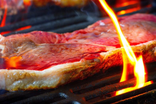 新鲜的红牛排烤架/烧烤与火焰和烟图片下载