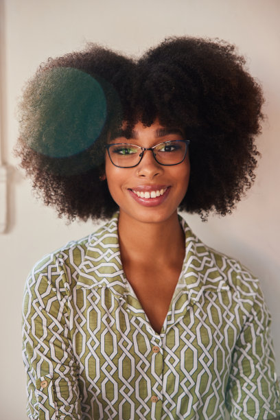 微笑的年轻女子戴着眼镜站在她明亮的工作空间图片下载