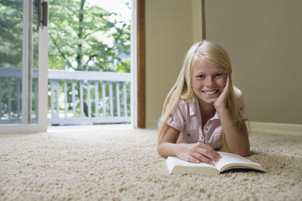 微笑的女孩躺在家里看书图片下载