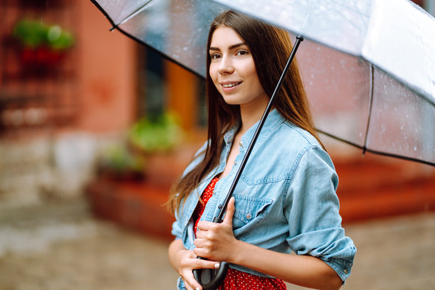 兴高采烈的女人撑着伞在外面散步。图片下载