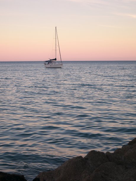 日落时帆船在海上航行的照片图片下载