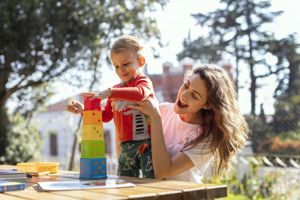 年轻女人和儿子在花园玩益智方块玩具图片下载
