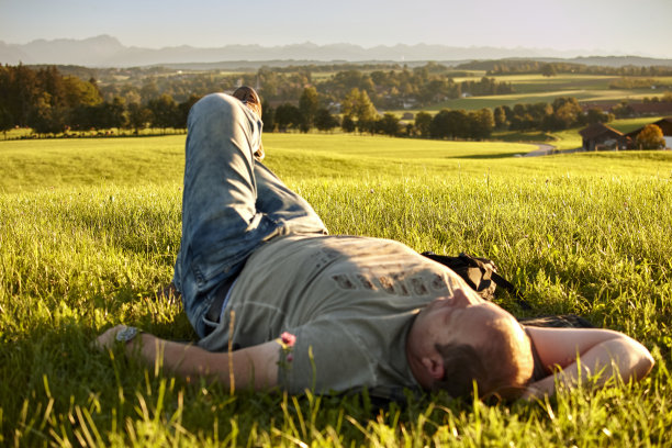 一个成熟的男人躺在绿色草地上图片下载