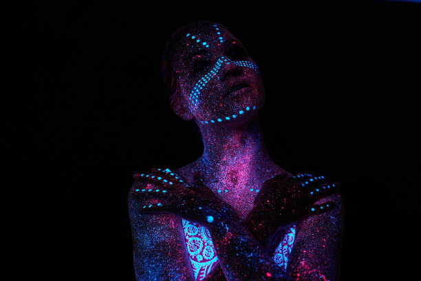 女人做瑜伽，手部运动，热身运动。紫外线下的艺术女孩宇宙。全身覆盖着彩色的水滴。星体瑜伽。噪音，焦点模糊图片下载