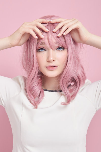 可爱的女孩长着粉红色的头发，染了头发。一个穿着白色裙子，粉红色背景的漂亮女人。染过的头发，完美的发型，美丽和护理图片下载