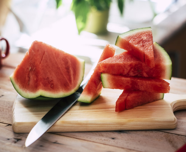 近距离观察成熟的新鲜西瓜片在砧板上的木桌，钢刀图片下载