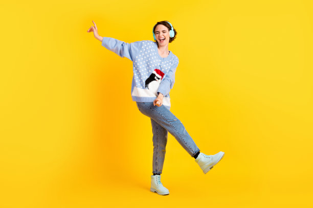 迷人的疯狂女士青年派对新年迪斯科听酷现代科技耳机舞池穿丑陋的毛衣牛仔裤鞋孤立的黄色背景的全长照片图片下载