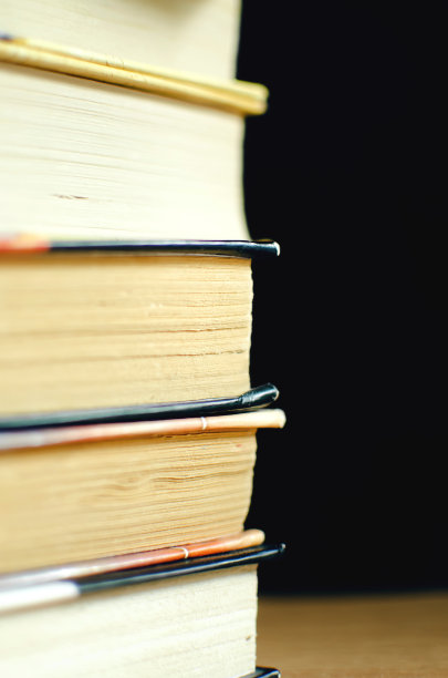 以黑暗为背景的一堆书。选择性对焦，垂直摄影。图片下载