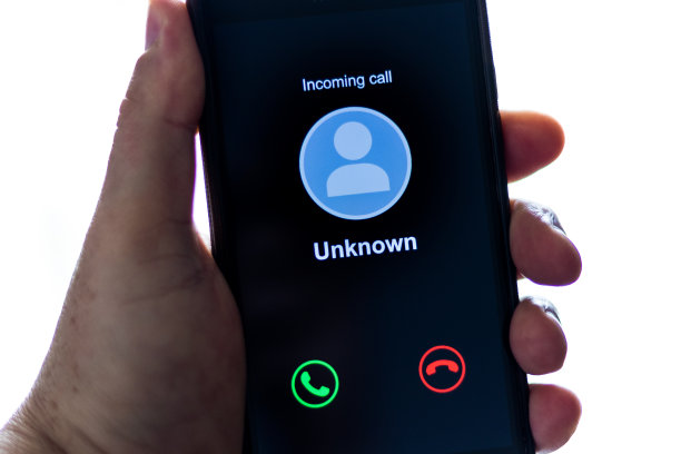 手持手机的男子接到未知电话-电脑屏幕背景和淡紫色的蓝色霓虹灯图片下载