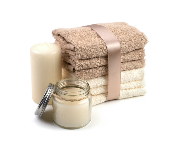 温泉套米色和白色毛巾与缎带，蜡烛和奶油，在白色的背景。图片下载